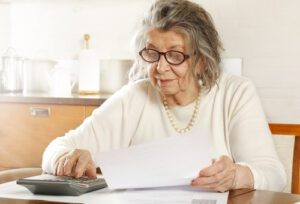 senior woman calculating Medicare late enrollment penalties