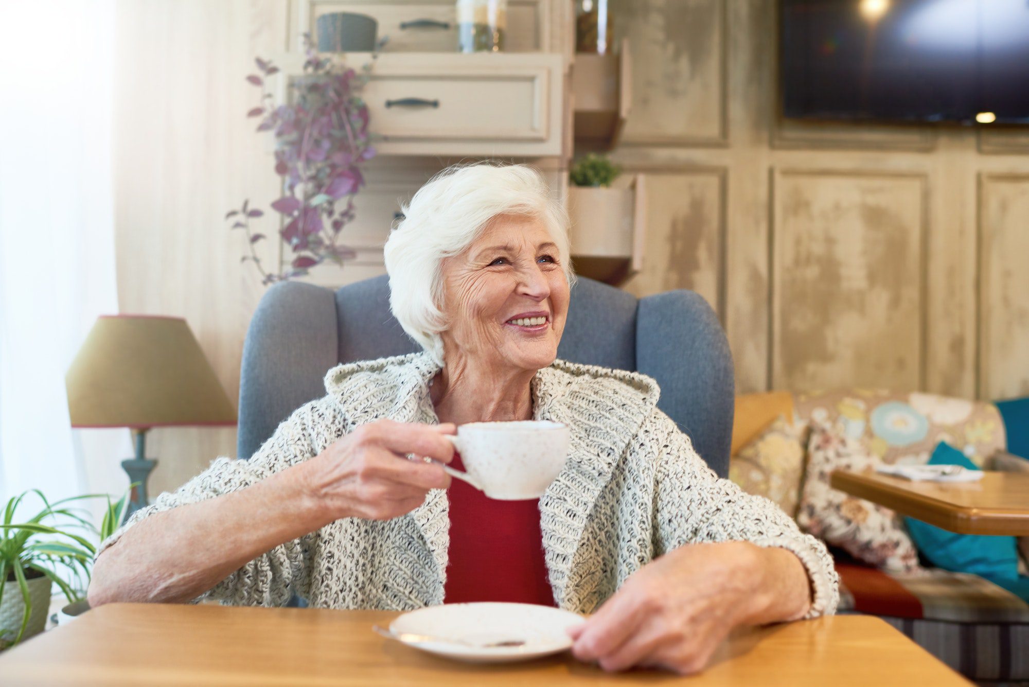 Happy senior lady enjoying tea as she discusses which Medicare Plan is right for her.