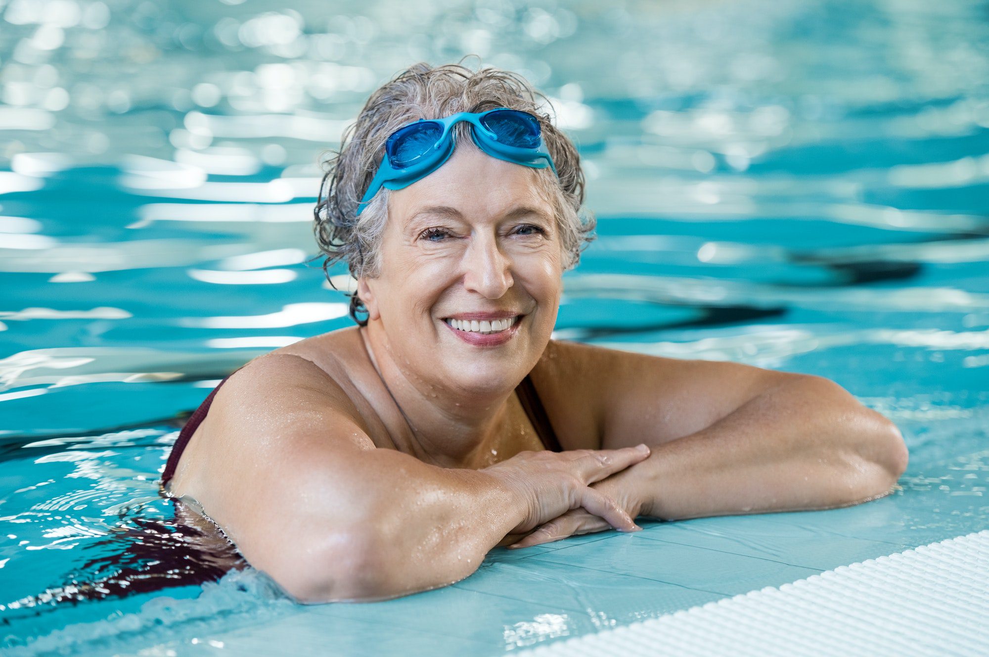 Elderly woman enjoying a swim as she thinks about what factors cause Medicare Supplement increases.