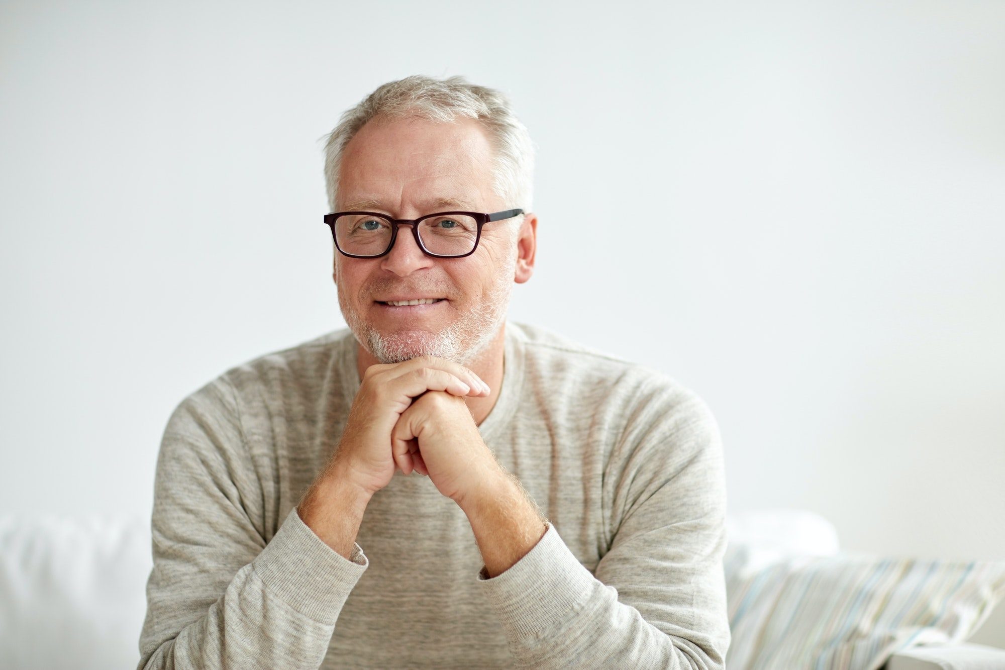 Smiling senior man in glasses sitting on sofa with Vision Benefits